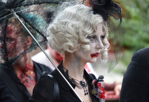 people dressed up as zombies - a woman with white wavy hair, black lacy parasol and black necklace