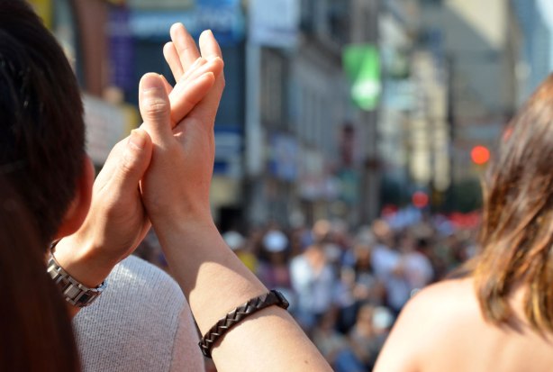 In the foreground a person is clapping, in the background is a crowd of people that are out of focus