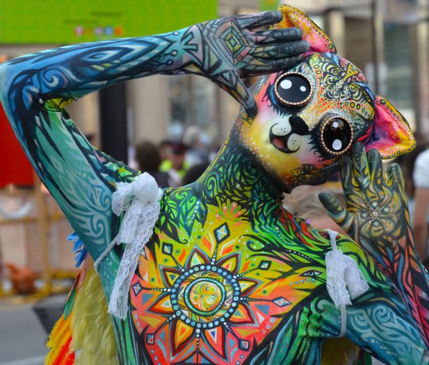 Meow Mur, a busker character dressed in a bright multicoloured leotard costume with cat like facial features. 