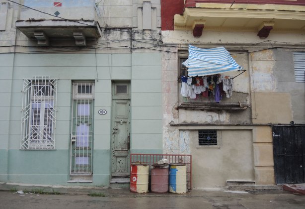 picture taken in the old part of the city of Havana Cuba - tall skinny doors at number 1104, colourful oil drums outside the door and laundry hanging from an upper window