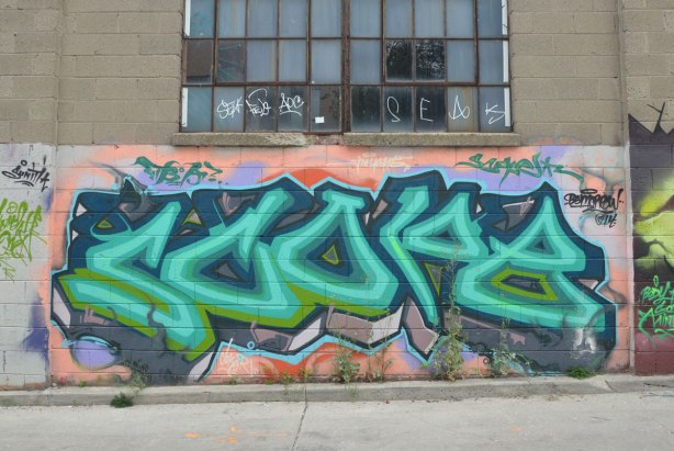 tag-like street art under a window in an alley