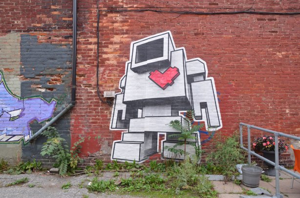 large wheatpaste lovebot on a brick wall 