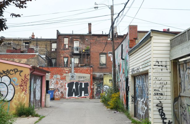 Buildings in an alley with lots of graffiti on them.