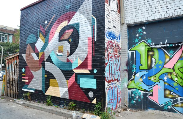 large geometric street art piece on a brick wall in an alley