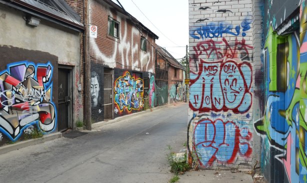 buildings in an alley with lots of street art on them 