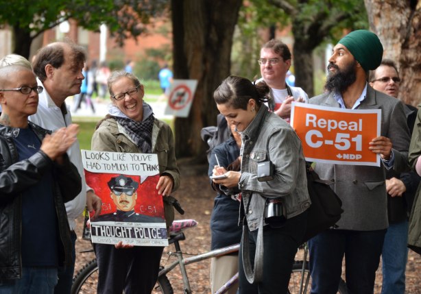 A woman reporter is talking to another woman at a protest rally. The woman being interviewed is holding a sign that says Thought Police, looks like you've had too much to think