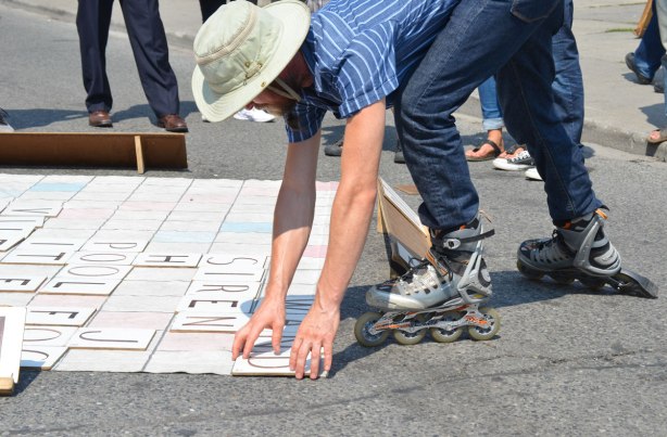 A man plays scrabble outdoors on the street while wearing roller blades