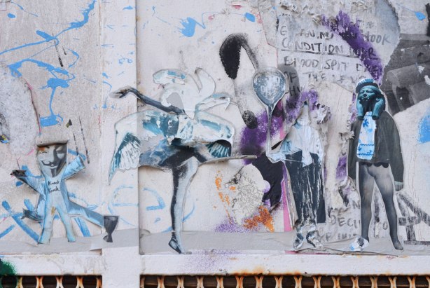 The remains of many black and white stickers or wheatpastes on a wall 