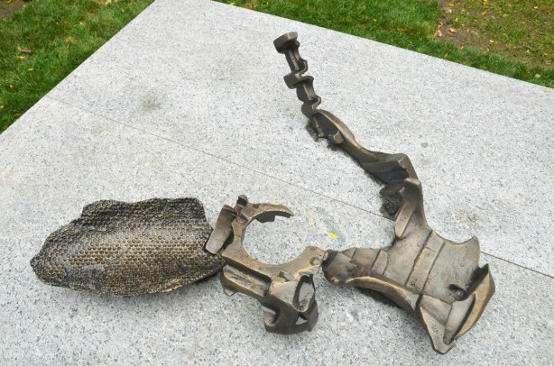 A metal sculpture by An Te Liu lying on a flat grey stone. 