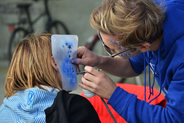 Before a Blue Jays baseball game at the ROgers Centre - a woman gets the words Go Jays Go painted onto her cheek in blue and white paint