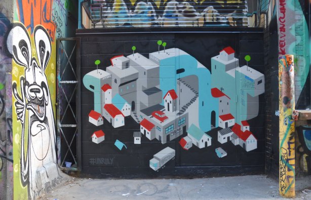 Street art piece by Peru of the word Peru written in block letters but also used as the backbone of a city scene of stylized little houses with red roofs. The painting has a little truck in front of the houses with the word waistoid on it. Street art Poser bunny to the left. 