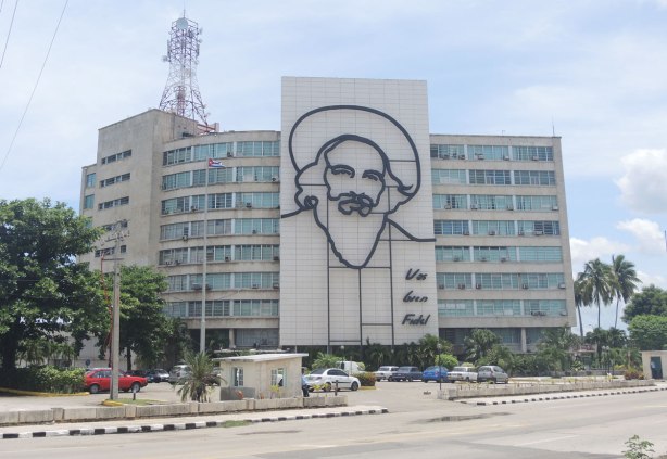 A multi storey building with a line drawing Fidel Castro's face as well as the words Vas bien Fidel