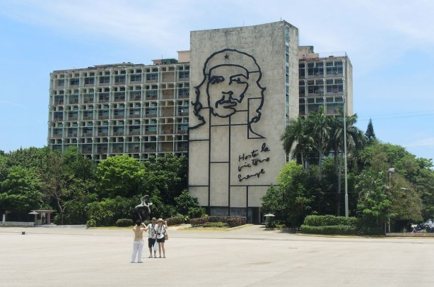 A multi storey apartment building. On the side is a very large outline drawing of Che Guevara's head and the words Hasta la victoria siempre