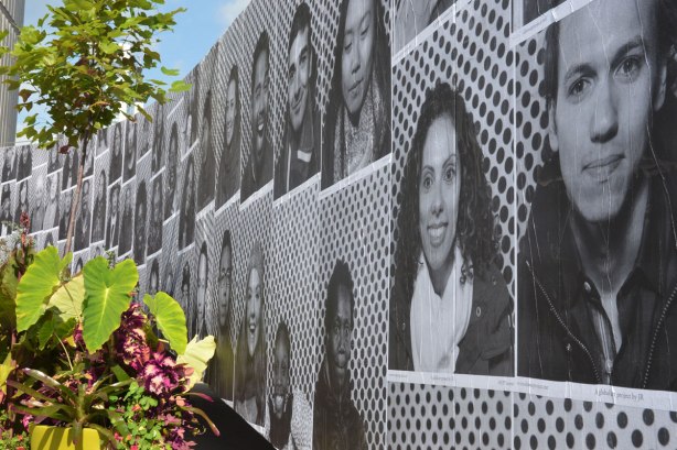 black and white photos of peoples faces glued to a wall, part of Inside Out Project in Toronto