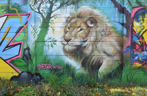street art mural by EGR of a lion beside a tree