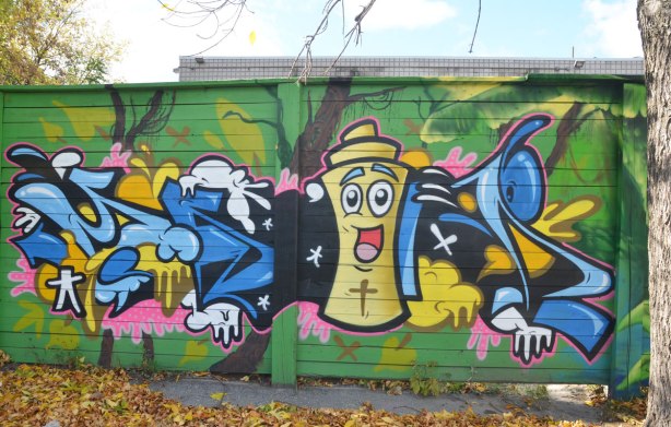 street art painting of a yellow spray paint can with a big happy face on it. 