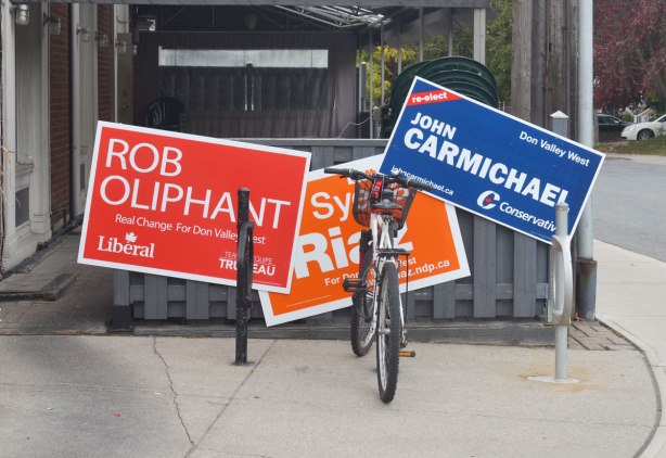 Three federal election campaign signs outside a restaurant, one each for the Liberals, Conservatives and NDP