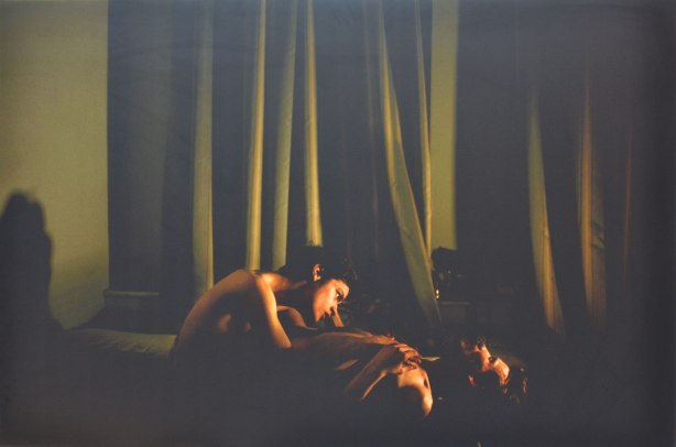 A photo by Mads Nissen, the winning photograph of the 58th World Press Photography Contest, Jon and Alex , two men, one lyng on his back and the other sitting beside him. The greenish curtains in the background dominate the picture. 