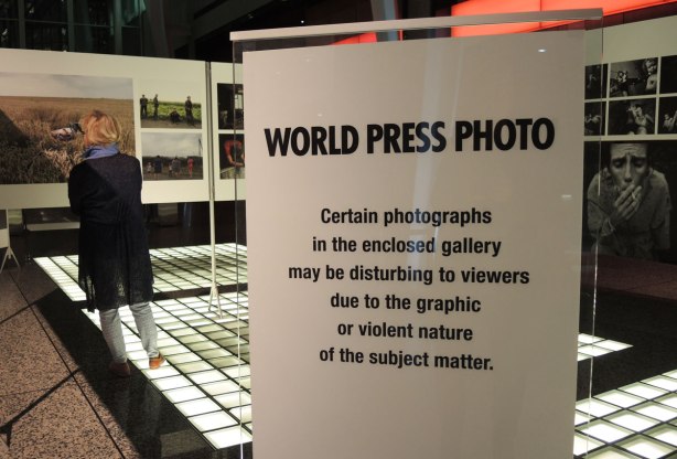 World Press Photo contest winners, sign cautioning people that the section they are about to enter has some disturbing images in it. 