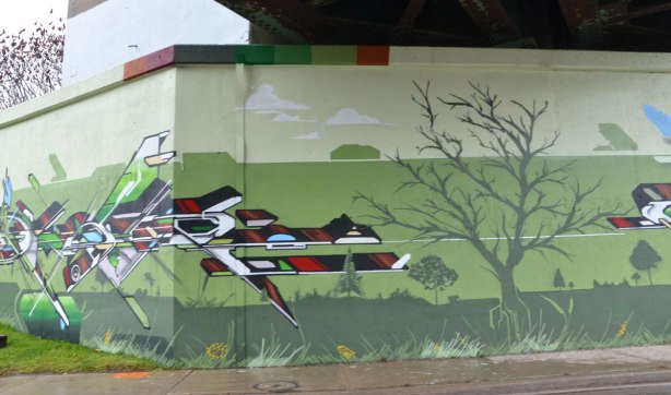 geometric shapes, dynamic shapes, mural on three toned green background on a railway underpass, painted by a group led by IAH Digital (Mediah) on Eglinton Ave