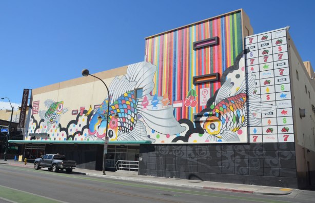 side of a three storey building on a corner in downtown Las Vegas. The upper storeys are covered with a mural, some multicolured fish, some vertical stripes