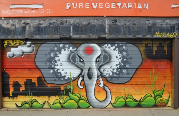 An elephant head and trunk street art painting by PUA (#PUA69) on a garage door. 
