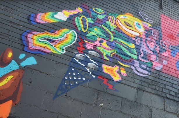 part of a mural high on a bright wall painted black. An ice cream cone and other sweet things. 