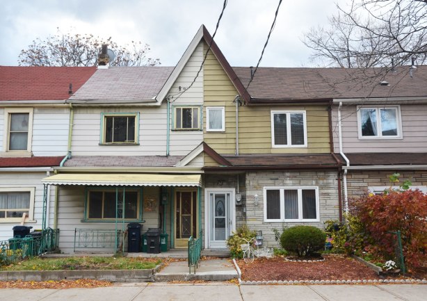 A group of row houses. In the middle are two semis that share a peaked roof but the semis are totally different. One has a pink roof the other has a brown roof. One is white and the other is green. One has a front porch but the other doesn't 