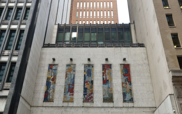 Five vertical panels of mosaics above the entrance of a downtown building, much taller buildings are on either side of it and behind it. Bell Canada building on Adelaide West, mosaics by York Wilson, communication theme public art