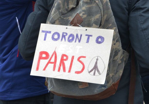 A sign on a backpack that says Toronto est Paris. Written in blue, white and red