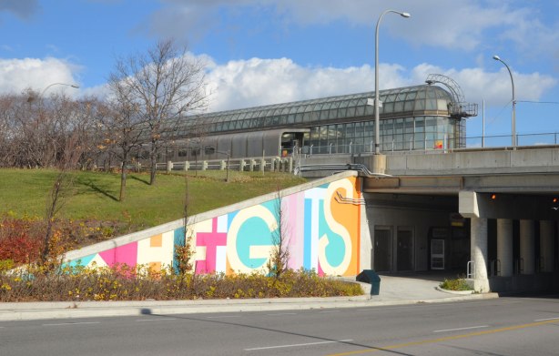 part of a mural on an underpass. There are four parts to the mural and each part is word painted in large capital letters in many colours - the word heights, with the south end of Yorkdale subway station in the picture 