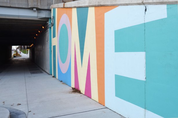 part of a mural on an underpass. There are four parts to the mural and each part is word painted in large capital letters in many colours - the word home