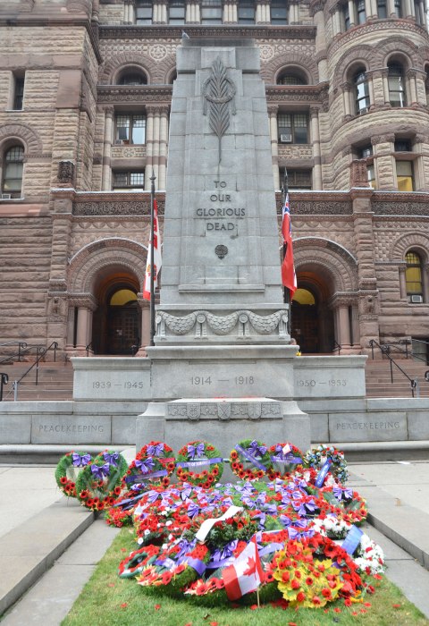 The cenotaph in front of Old City Hall in Toronto, with a collection of wreaths that have been laid at the bottom of it.