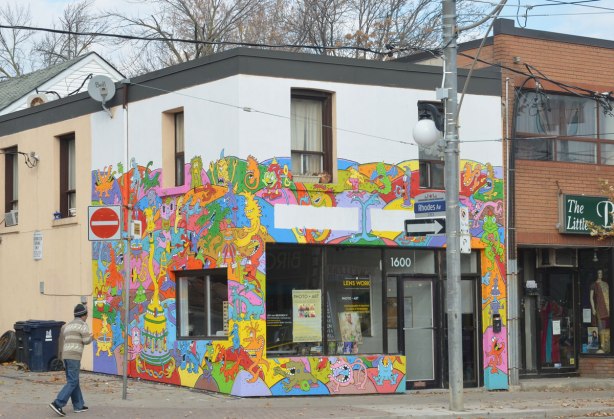A store on the corner of Gerrard and Rhodes in Toronto where the front and side of the building are covered with multicoloured street art. 