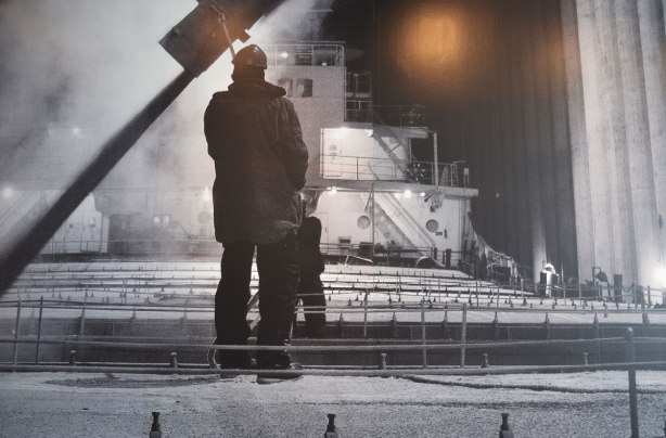 close up of part of a very large black and white photograph of a man standing on the deck of a lake freighter at night in the winter