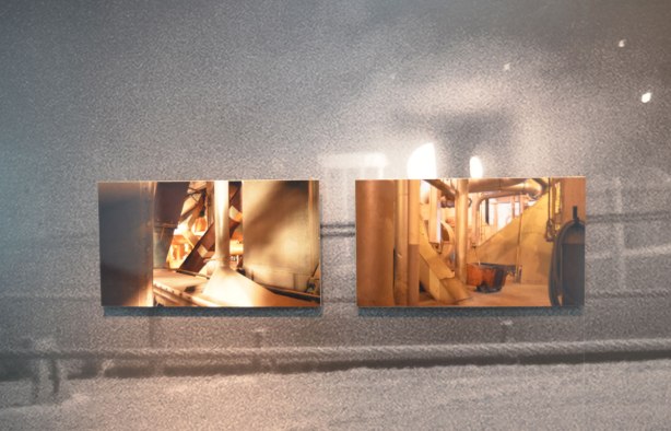 Two photographs of parts of a ship mounted on a wall that is covered with a large black and white photo