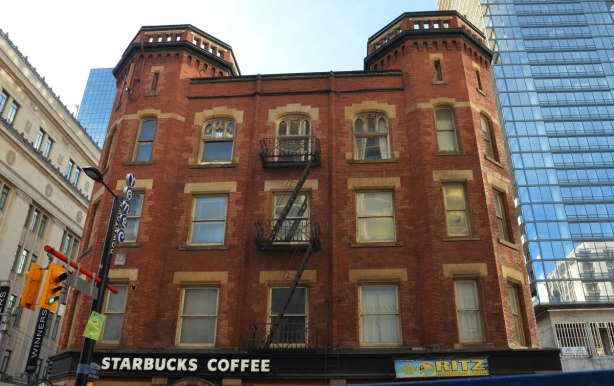 Oddfellows Hall, a large brick building with two hexagonal turrets, brick, now a Starbucks on the ground floor. 
