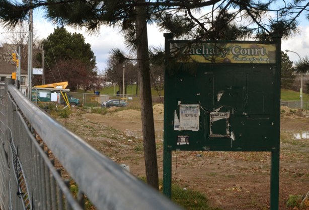 An old sign for community notices that is now empty because the area is fenced off for demolition