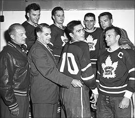 Old black and white picture from the Hockey Hall of Fame, showing Syl Apps (after retirement from hockey) and George Armstrong after Armstrong was given number 10 Maple Leaf jersey to wear. 