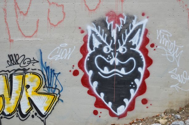 graffiti under a bridge, black deveilish face with horns, beard and teeth, black face, white details, red around it