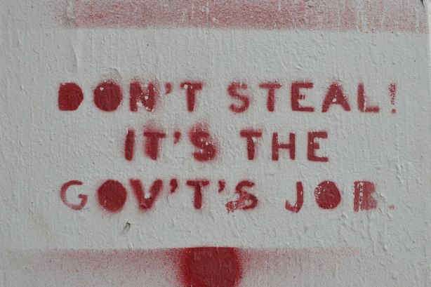 stencil, on concrete, in red, words that sat: Don't steal it's the gov't's job