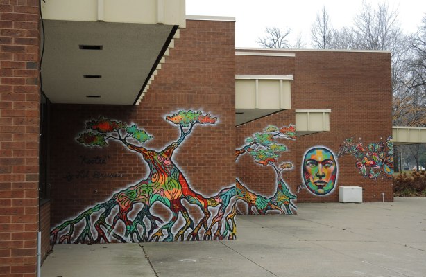 murals on three walls at the Driftwood Community Centre, two trees and a large face