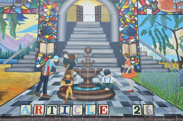 education mural, stairwell with fountain in front of it, stained glass windows on either side