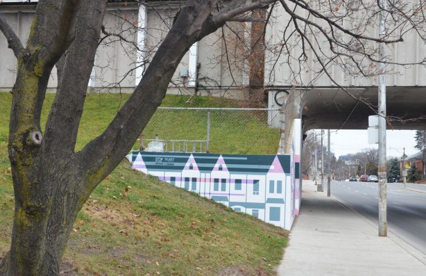 part of a mural by Rob Matejka and Tommy Matejka on the wall on a TTC subway underpass at Keele, a mural of houses on a street, looking north on Keele Street