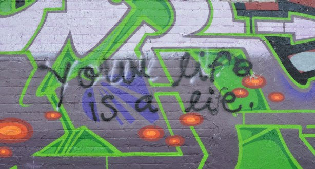Someone has scrawled Your life is a lie in black over a piece of street art. Someone else has changed lie to life by adding an f