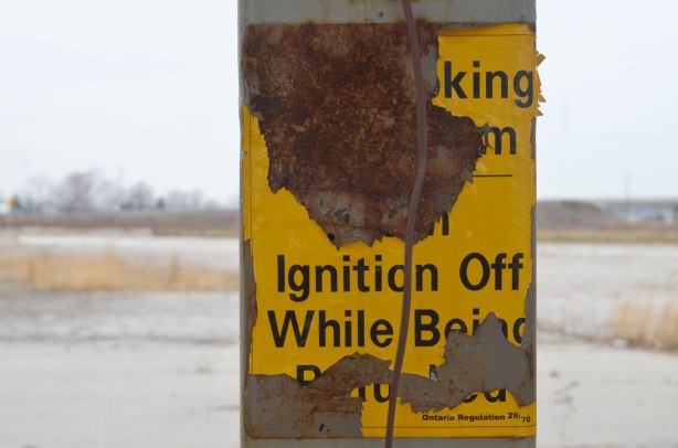 rusted old sign at a gas station that warns you to turn off your ignition while refueling your car
