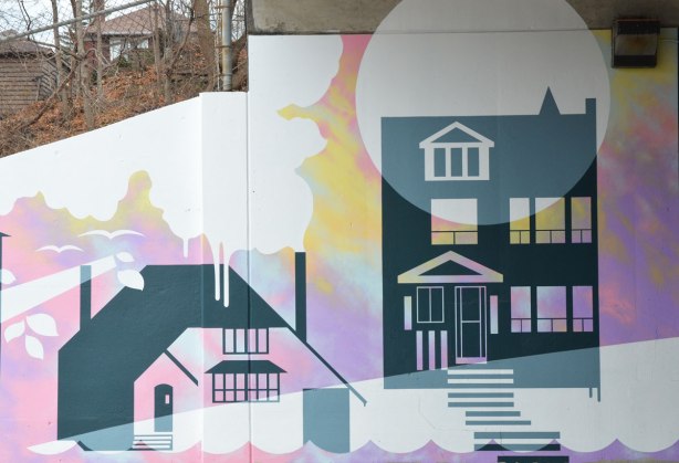 part of a mural showing two houses, with two real houses in the background