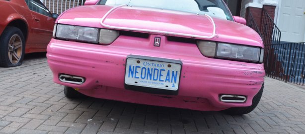 the back of a bright pink car with the license Neon Dean