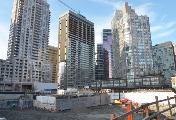 a large number of new high rise buildings just beyond a large hole in the ground where another condo is being built