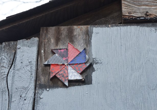 8 sided pinwheel in reds and blues fixed against the top corner of a shed or garage wall in a lane 